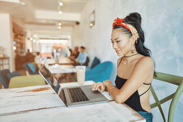 a young asian woman using her laptop in cafe