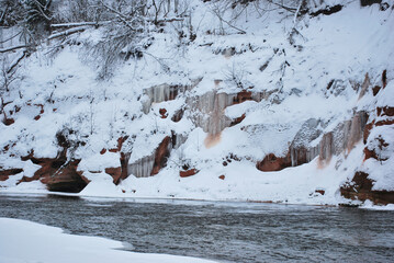River in the winter near icicle full rocky cliff