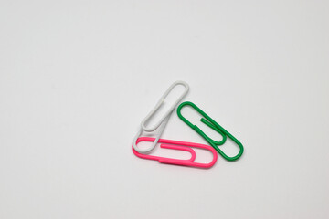Three paper clips. White background, close-up, isolated.