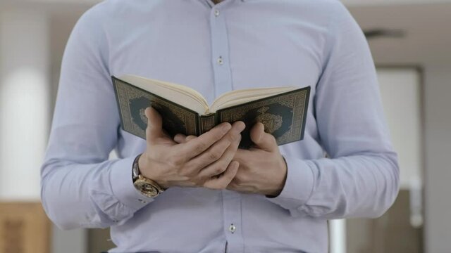 Closeup on a muslim man reading holy Quran. Muslim man sit reading the book and pray prayer by hand in the Mosque (Masjid), Belief Quran culture. 