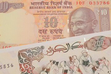 A macro image of a orange ten rupee bill from India paired up with a beige 200 Algerian dinar bank note.  Shot close up in macro.