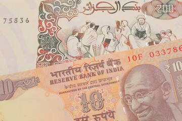 A macro image of a orange ten rupee bill from India paired up with a beige 200 Algerian dinar bank note.  Shot close up in macro.
