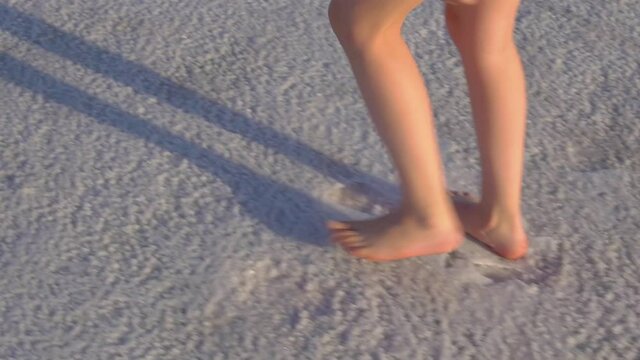 A girl walks through the snow, on a salt lake in the summer