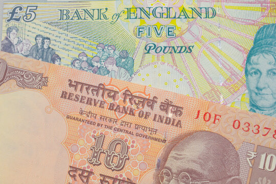 A macro image of a orange ten rupee bill from India paired up with a colorful, five pound bank note from the United Kingdom.  Shot close up in macro.