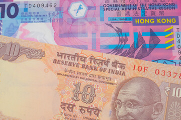 A macro image of a orange ten rupee bill from India paired up with a pink and purple, plastic ten dollar bill from Hong Kong.  Shot close up in macro.