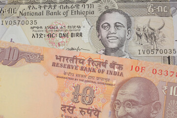 A macro image of a orange ten rupee bill from India paired up with a grey Ethiopian one birr bill.  Shot close up in macro.