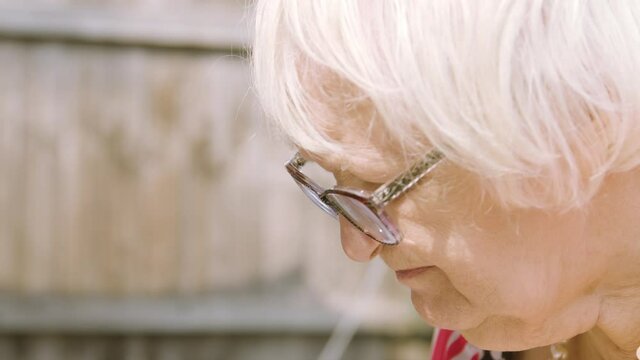 Close up on elderly woman's face as she types and makes a mistake garden day