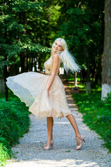 Young beautiful blonde girl in beige dress, summer park outdoor