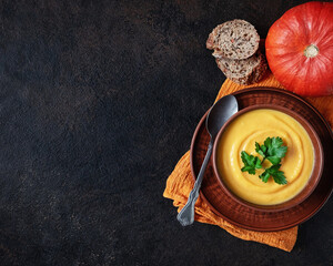 Pumpkin soup on a black stone background. Top view. Space for copying.