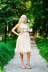 Obraz na płótnie Canvas Young beautiful blonde girl in beige dress, summer park outdoor