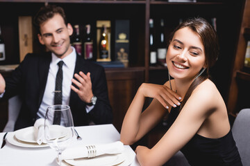 Selective focus of young woman looking away near boyfriend during dating in restaurant