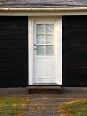 Isolated White Door on Black Wooden House
