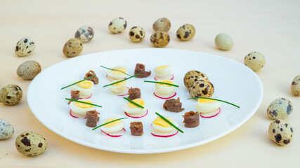 boiled quail eggs with anchovies and chives on a plate