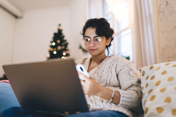 Young woman with laptop and smartphone in living room