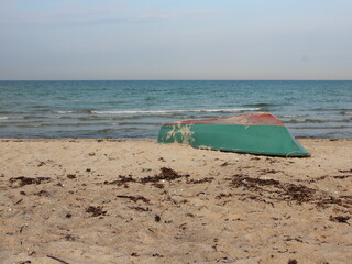 Fototapeta na wymiar Green Rowing Boat Upside Down on Beach