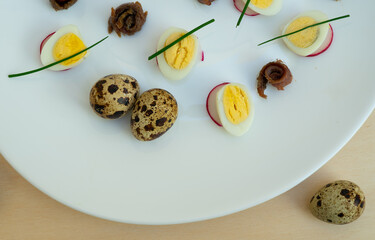 boiled quail eggs with anchovies and chives on a plate