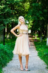 Young beautiful blonde girl in beige dress, summer park outdoor