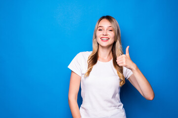 Fototapeta premium Smiling pretty young woman showing thumbs up on the blue background