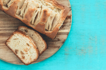 Apple sponge cake cut on a kitchen table on a blue background. Copy space. Baking concept.