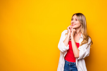 Portrait of a smiling blonde young woman standing over yellow background