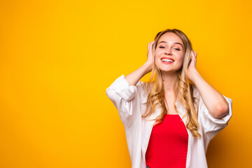 Portrait of a smiling blonde young woman standing over yellow background