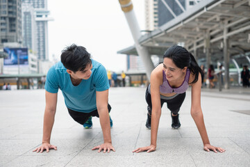 Young asian couple athlete in sportswear exercising with push up in the city