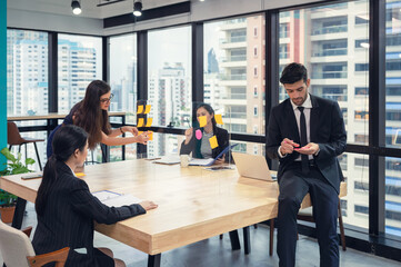 Multi ethnic business team brainstorming with post it note paste up on conference board in coworking space