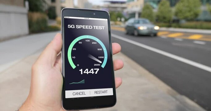 A man in a city tests his cellular 5G download bandwidth speed on a mobile phone. Traffic and taxi cabs pass in background. Fictional interface speedometer gauge created in After Effects.  	