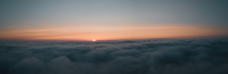 Fototapeta na wymiar Aerial morning sunrise view over the clouds in the air with ocean fog and glowing clouds