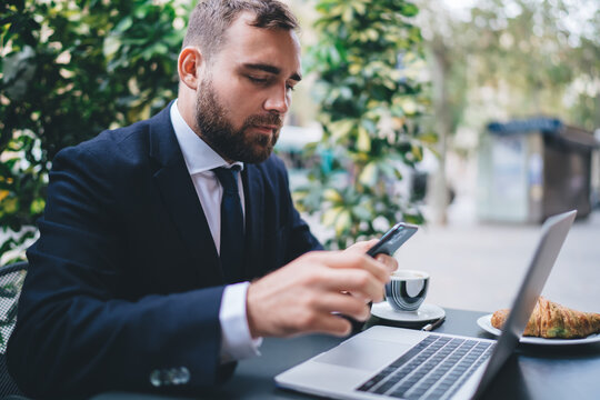 Businessman using smartphone and laptop in cafe