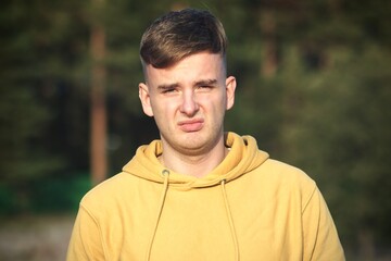 Portrait of young disappointed offended young man looking at camera with upset frustrated look outdoors
