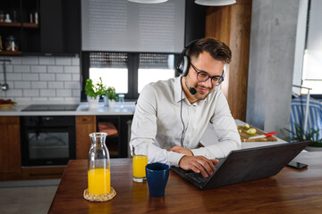 Young handsome man working from home, sitting in front of laptop computer having meeting over internet. Businessman freelance entrepreneur. 