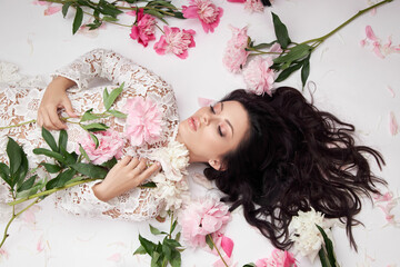 Beautiful brunette woman with peony flowers. Natural cosmetics and makeup, perfect skin