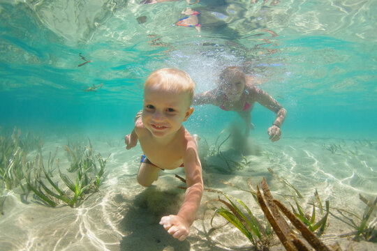 Young mother with child dive in sea lagoon to explore underwater world. Family travel lifestyle in summer adventure camp. Swimming activities on beach vacation with kids.