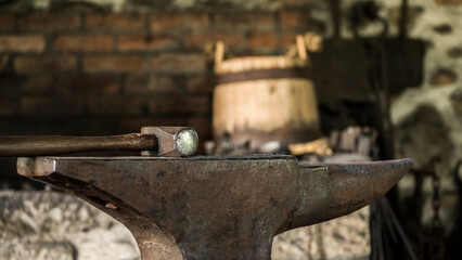 Equipment of the old forge - anvil and hammer, in the background a wooden bucket