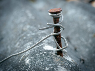 Obraz premium rusty nail wrapped with aluminum wire in slate