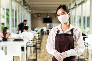 Fototapeta na wymiar Portrait of waitress with facemask in New normal restaurant background