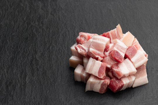 Belly pork slices on black stone background
