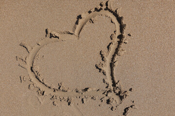 Heart is drawn on wet sand on beach. Services of travel companies concept