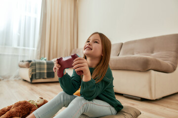 A small cute girl enjoy playing videogames smiling holding a gamepad while sitting on a floor