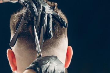 Cropped shot of barber cutting hair of customer with scissors