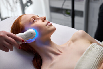 adorable young woman enjoying electric microcurrent massage by cosmetologist, hardware modern facelifting procedure in beauty salon. skin care concept, healthy lifestyle