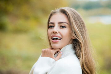Naklejka premium Autumn trend. Beautiful woman fashion model having fun in fall park outdoors. Pretty tenderness model girl looking at camera.