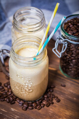 Iced coffee with milk in vintage jar on old wooden table