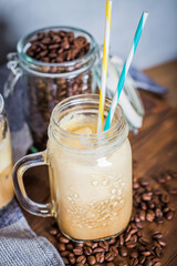 Iced coffee with milk in vintage jar on old wooden table