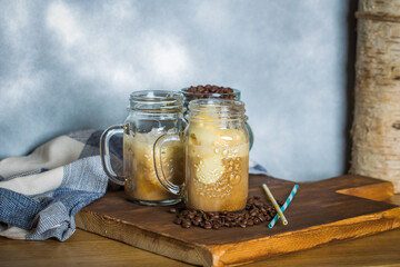 Iced coffee with milk in vintage jar on old wooden table