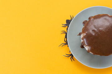 Halloween concept, trick or treat. Spiders crawl out from under a plate. Chocolate cake lies on the right. Orange background, handmade cooking. Copy space, flat lay. Selective focus, blur.