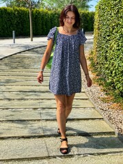 Beautiful young woman in blue dress walks through park in Krasnodar