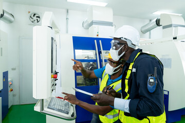 Professional engineer wearing a hard hat and safety glasses operating CNC milling machine in manufacturing workshop. Male worker working on a lathe machine in metal industry factory on business day.
