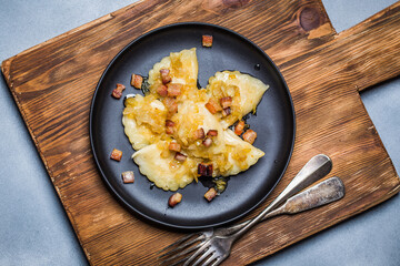 Dumplings with meat, onions and bacon on black plate. Traditional Polish dumplings